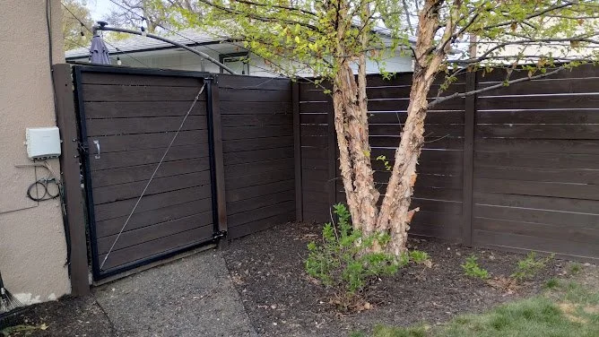 Dark walnut-stained fence with mature landscaping