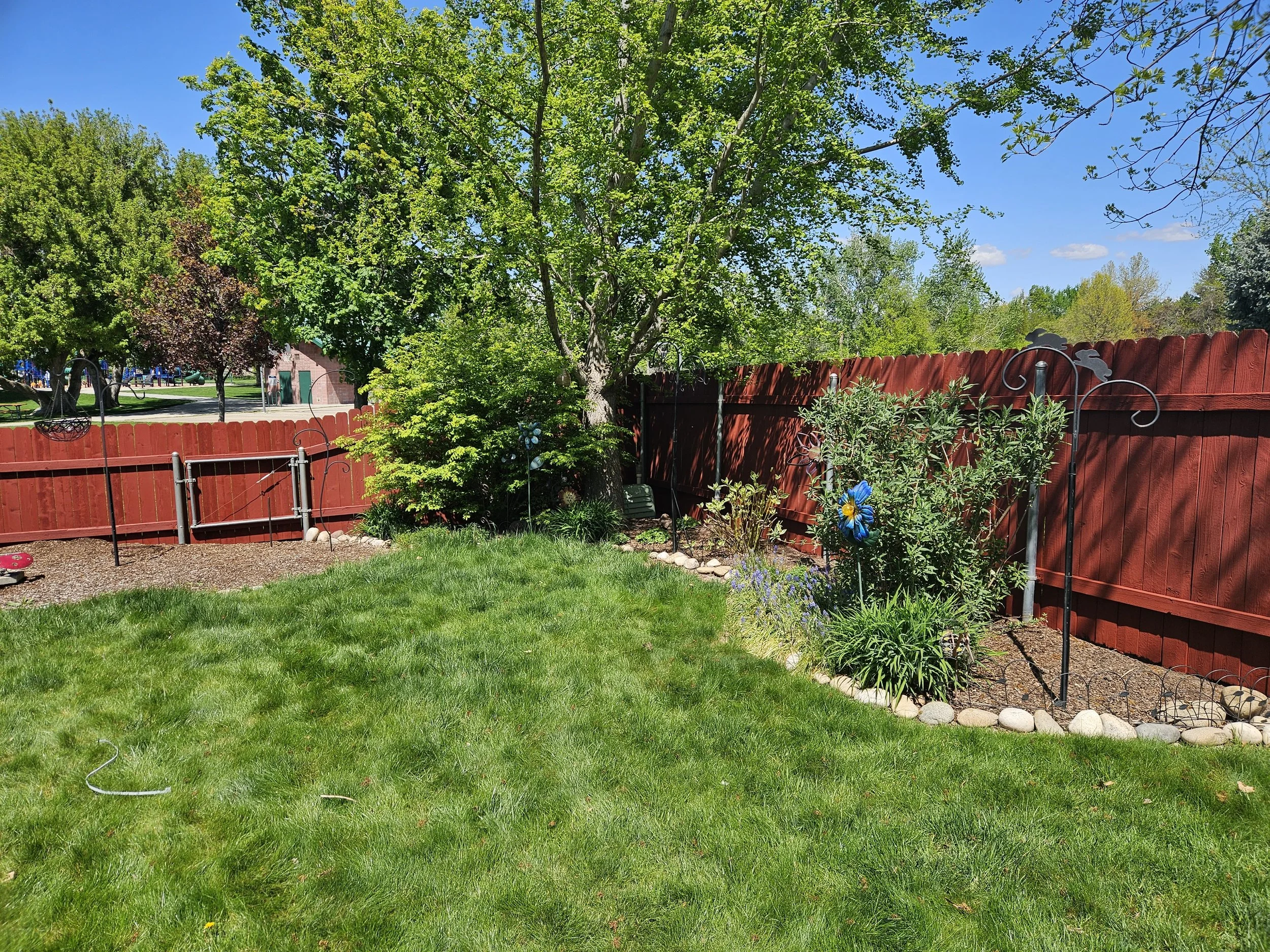 Solid red fence stain around a manicured lawn